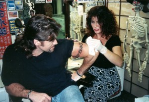 Thanks to a tip from Heidi Mark, whose real life boyfriend is the heavily tattooed Vince Neil of Motley Crue fame, it was off to Sunset Tattoo on the world famous Sunset Strip in Hollywood. Cyrus opted for a black tribal armband on his left bicep from ink-slinger to the stars, Lisa Bernabe, whose clients include Dennis Rodman, LL Cool J., baseball star Bobbie Bonilla, Robin Quivers from the Howard Stern Show, actor Daniel Baldwin, to name a few.